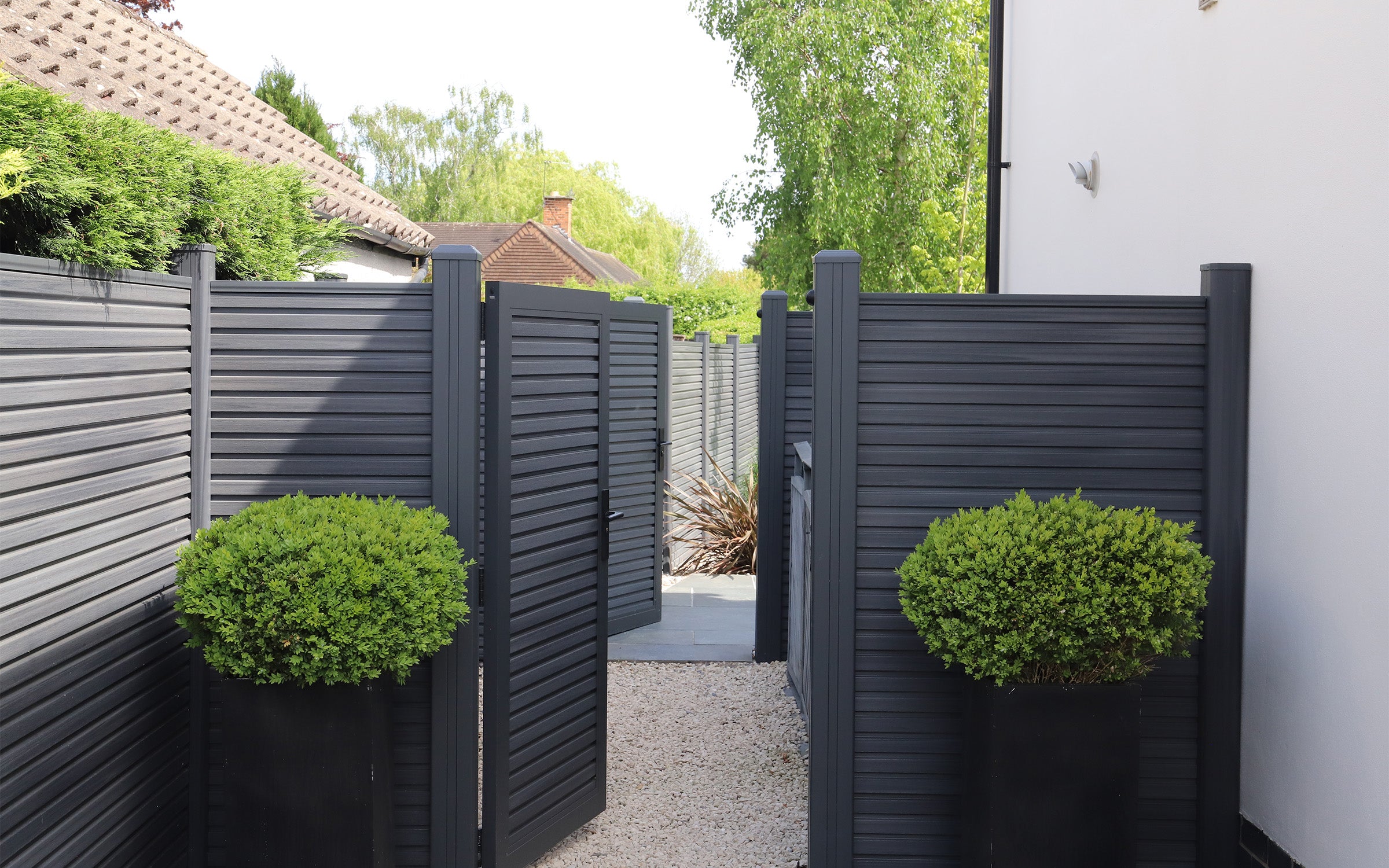 composite fence with open matching gate, leading to a garden area