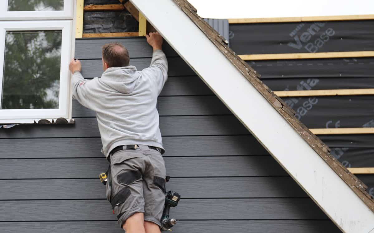 man installing composite cladding onto front of home